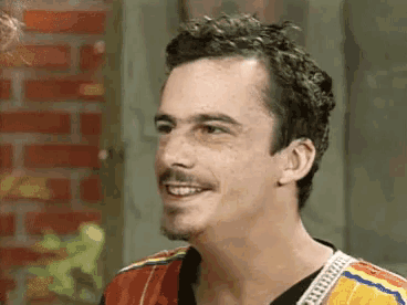 a man with a mustache is smiling while wearing a colorful jacket .