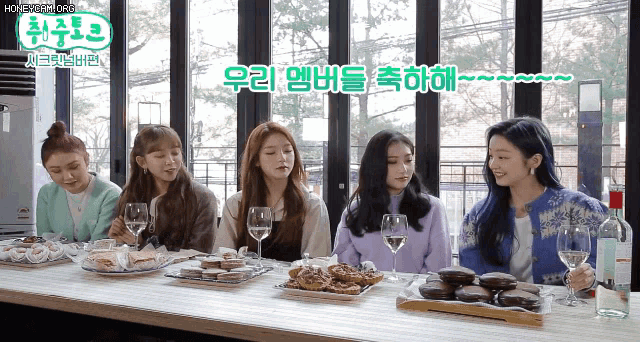 a group of women sitting at a table with plates of food and wine glasses