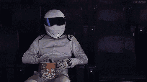 a man wearing a helmet is eating popcorn in a movie theater .