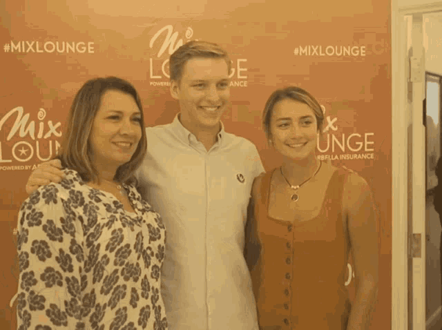 a man and two women pose for a picture in front of a wall that says #mixlounge