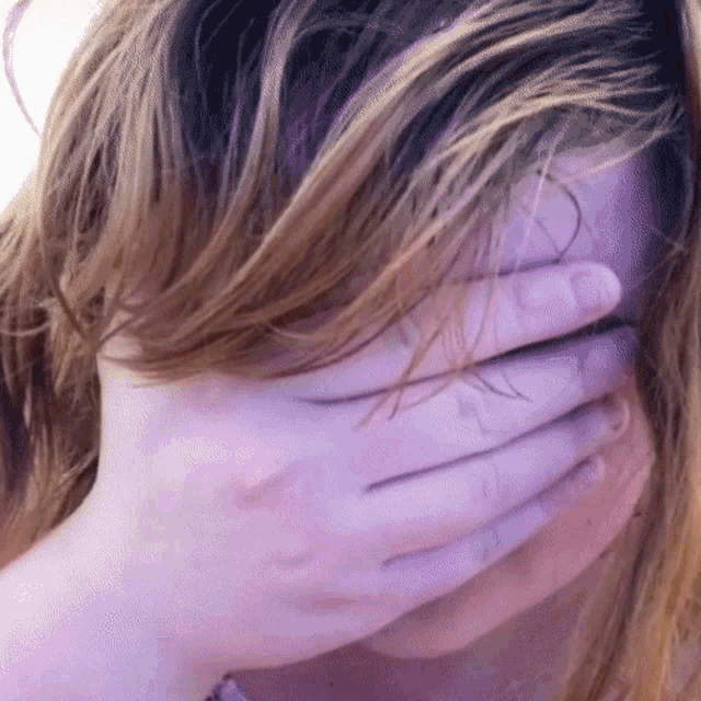 a woman covering her face with her hand in purple
