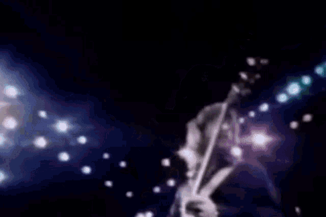 a man is playing a guitar on a stage in a dark room .