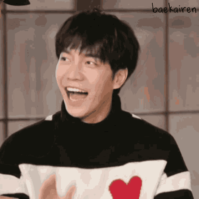 a young man wearing a black and white sweater with a red heart on it