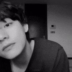 a black and white photo of a young man 's face in a room .