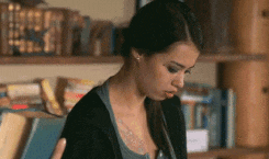 a woman with a tattoo on her chest is standing in a library .