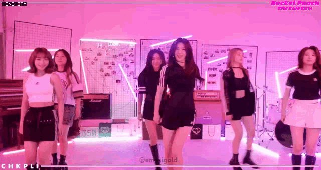 a group of girls are dancing in a room with pink lights and the words rocket punch fin ban sen on the bottom