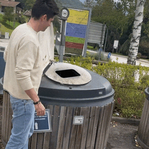 a man looking into a trash can with a sign that says packaging on it