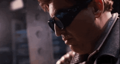 a close up of a man wearing sunglasses and a leather vest .