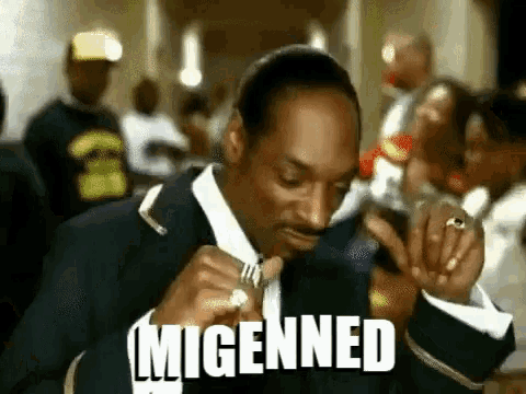 snoop dogg is wearing a suit and tie and smoking a cigarette in a crowd .