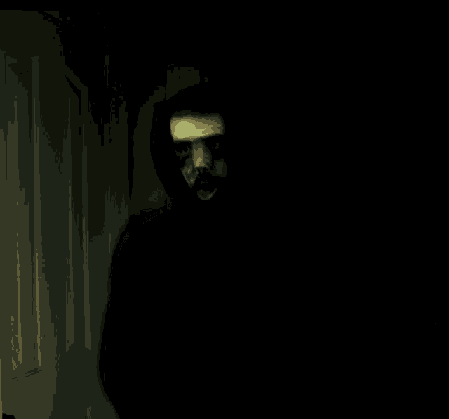 a person with yellow gloves on covering their face in the dark