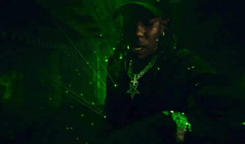 a person is standing in a dark room with green lights coming out of the ceiling