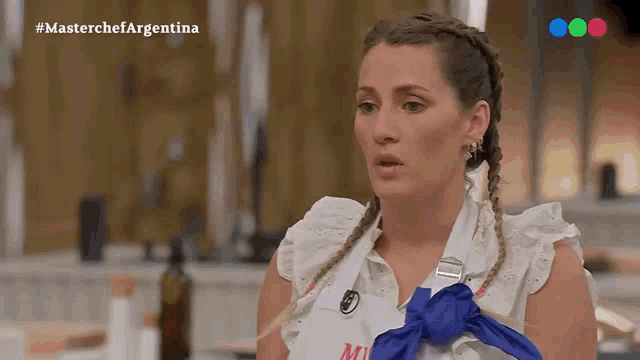 a woman wearing a white shirt with a blue tie around her neck is on a television show called masterchef argentina
