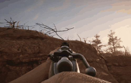 a person is holding a sniper rifle on a rocky hillside