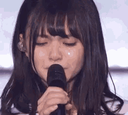 a woman is crying while holding a microphone in her hand .