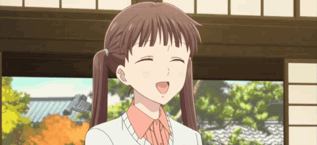 a cartoon girl with pigtails is smiling with her eyes closed .