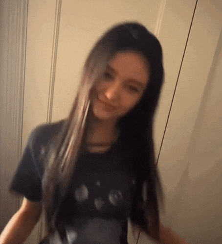 a woman with long dark hair is wearing a black t-shirt and smiling .
