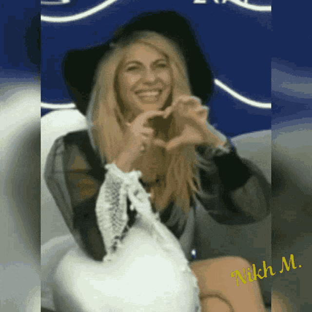 a woman is making a heart shape with her hands and the name nikh m. is on the bottom