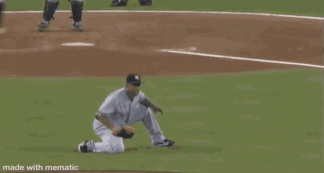a baseball player is kneeling on the field while holding a glove .