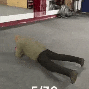 an older man is doing push ups on the floor in a gym .