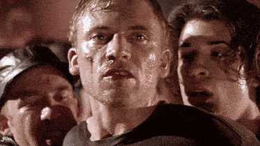 a man with a bloody face is surrounded by other people