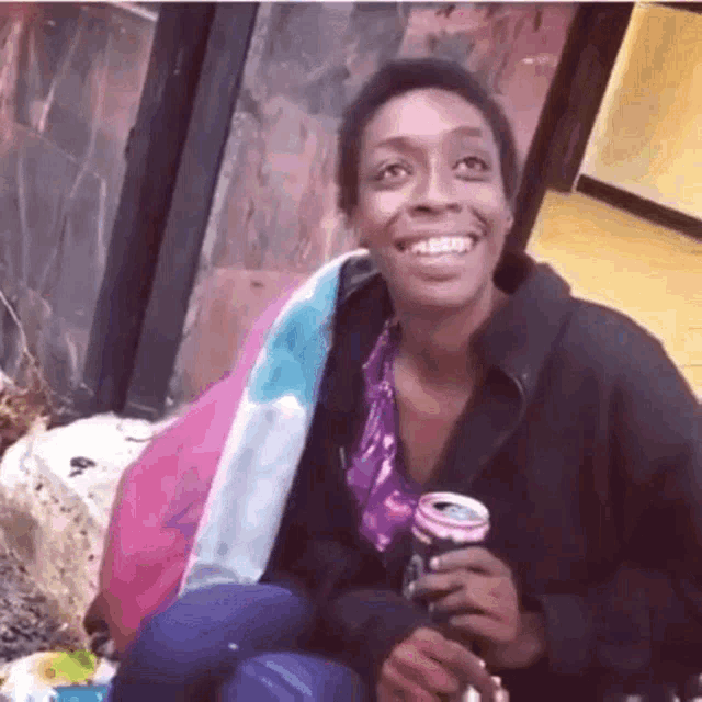 a woman is smiling and holding a can of soda