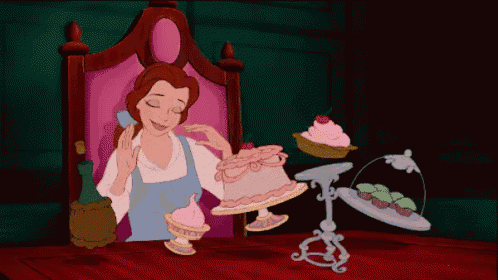 belle from beauty and the beast is sitting at a table with cupcakes and cakes
