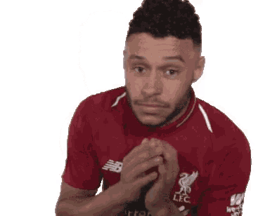 a man in a red shirt is making a funny face while holding his hands together .