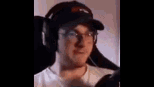 a man wearing headphones and a baseball cap is sitting in a chair .
