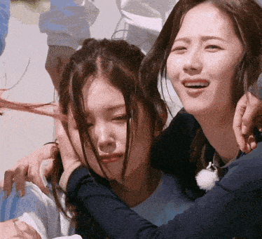 two women are hugging each other and one of them is smiling