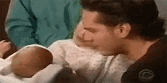 a man in a hospital gown is holding a newborn baby