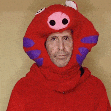 a man wearing a red pig costume with purple ears