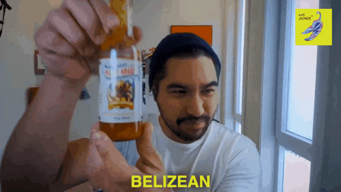 a man holding up a bottle of belizean sauce