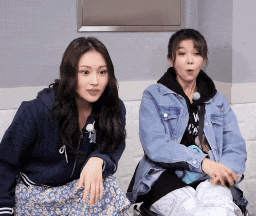 two women sitting next to each other with one wearing a hoodie that says ' w ' on it