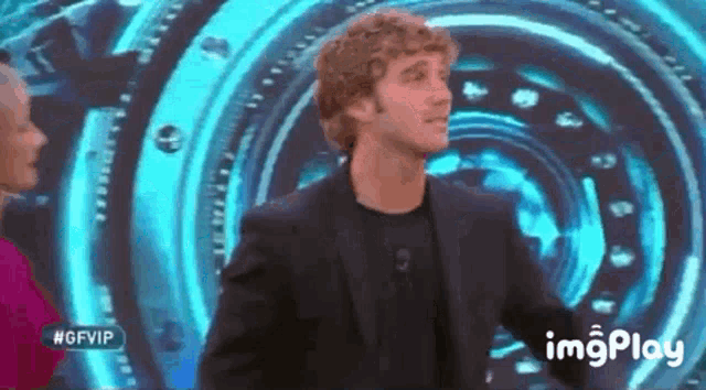 a man in a suit is standing in front of a blue circle and a sign that says #gfvip .