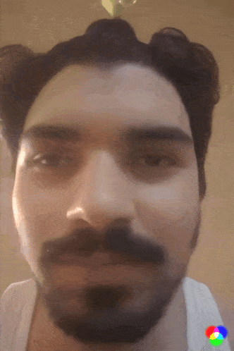 a close up of a man 's face with a beard and buns in his hair