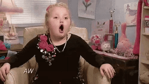 a young girl is sitting in a chair with her mouth open .