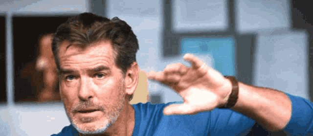 a man with a beard wearing a blue shirt is making a funny face