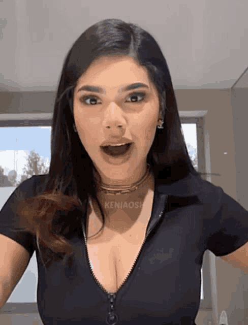 a woman is wearing a black shirt with a zipper on the front and a choker that says keniaose on it