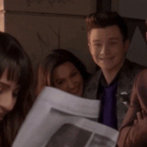 a man in a purple tie is holding a newspaper