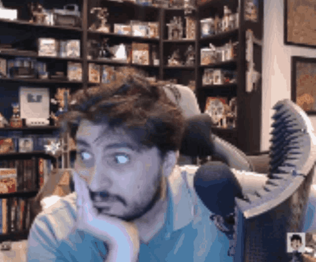 a man with a beard is sitting in a chair with his hand on his face