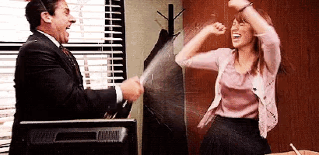a man and a woman are standing next to each other in an office .