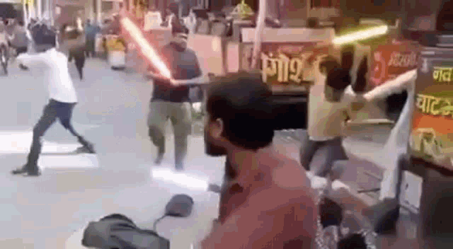 a group of men are fighting with lightsabers in a street .
