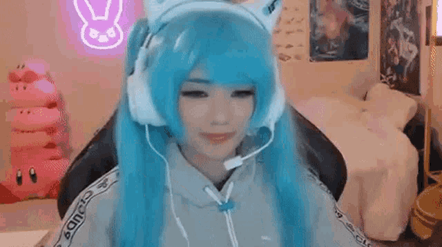 a woman wearing a blue wig and headphones is sitting in a chair in a room .