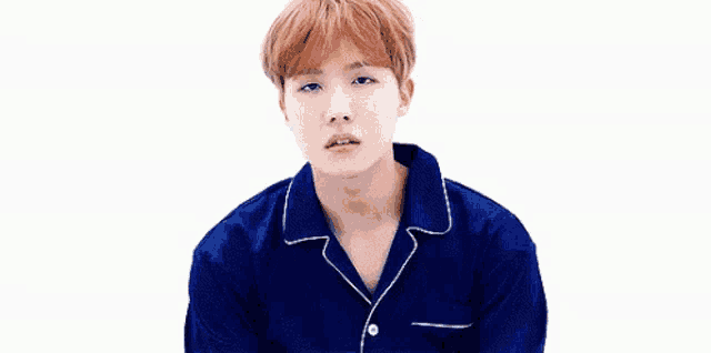 a young man with red hair is wearing a blue pajama shirt and looking at the camera .