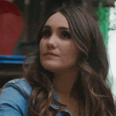 a close up of a woman 's face with long hair wearing a blue denim jacket .