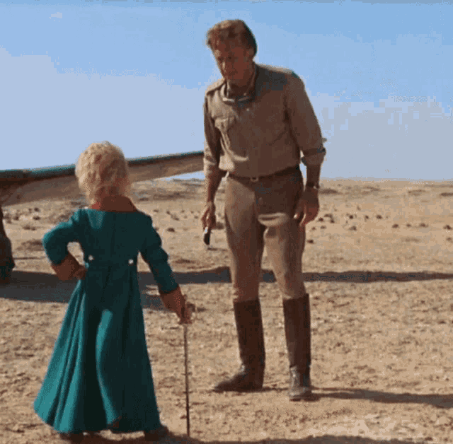 a man and a little girl are standing in the sand