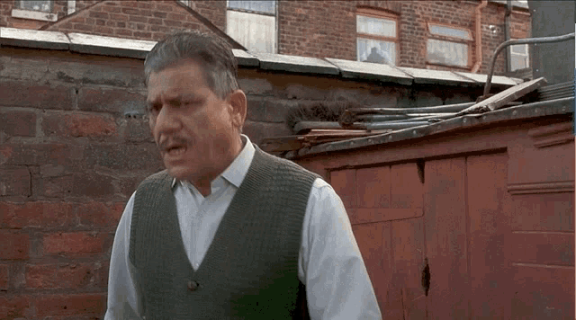 a man in a green vest is standing in front of a red garage door