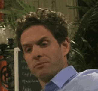 a man in a blue shirt is making a funny face in front of a sign that says caffe macchiato