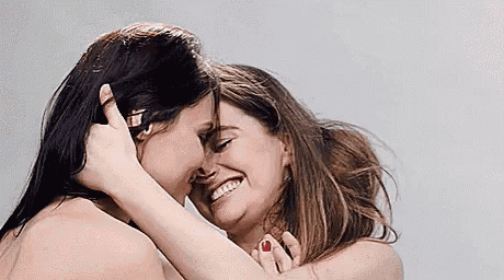 two naked women are hugging each other and kissing each other .