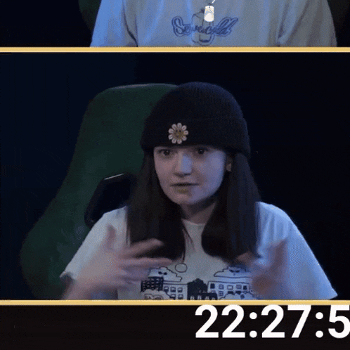 a girl wearing a black beanie with a flower on it is sitting in front of a screen that says 22:27